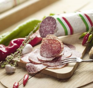 PICK original ungarische Salami angeschnitten auf Holzbrett mit Gewürzen und Paprika