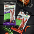 Verpackungen von PICKSTICK mild und pikant nebeneinander auf einem Holzuntergrund
