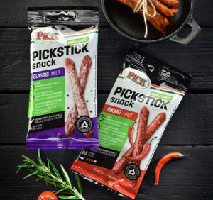 Verpackungen von PICKSTICK mild und pikant nebeneinander auf einem Holzuntergrund